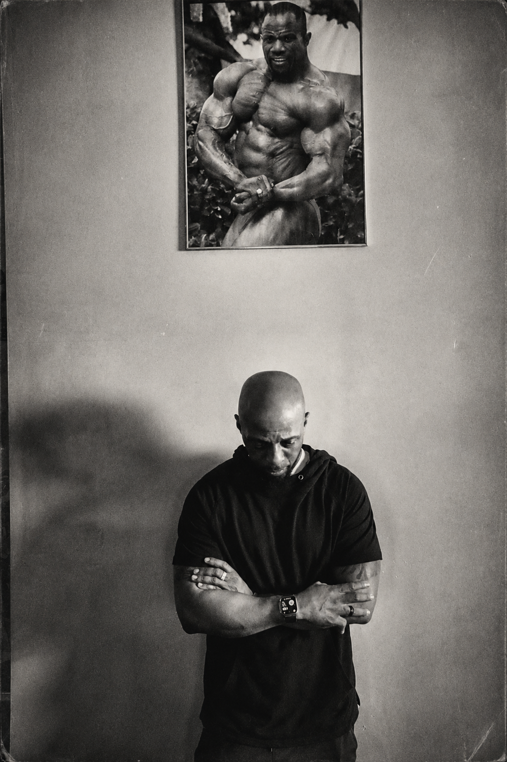Athlete beneath a bodybuilder poster, black and white — fitness brand photography