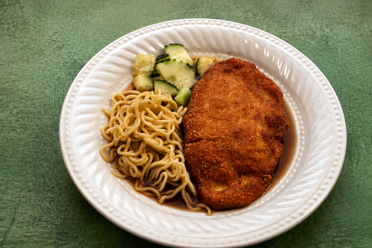 IBU: Breaded cutlet with noodles and cucumber — Indonesian restaurant food photography